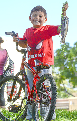 Survey indicates fishing even better in New Mexico (boy with fish and a bike)