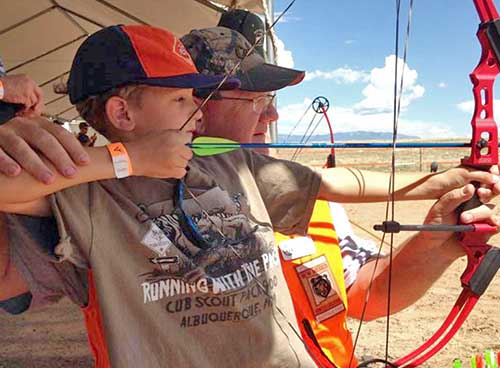 Become a Wildlife Conservation Volunteer. (Photo of archery instructor helping youth). New Mexico Department of Game and Fish